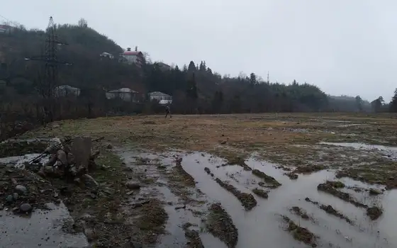 Земельный участок на берегу реки в тихом районе с видом на горы.