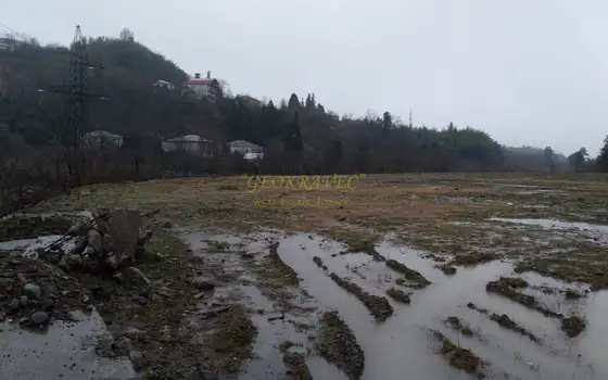 Земельный участок на берегу реки в тихом районе с видом на горы.