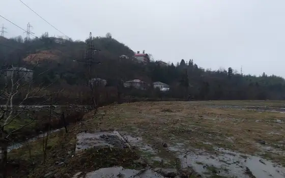Земельный участок на берегу реки в тихом районе с видом на горы.